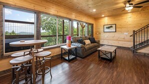 A wooden interior with a sofa, chairs, a table, and a staircase. - Nature’s Ridge | Modern Cabin + Stunning Views (Sevierville)
