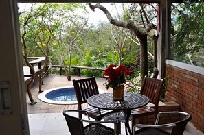 An outdoor patio with a round table, chairs, a small pool, and a wooden deck. - Ferradura Parque Pousada (Búzios)