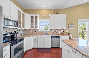 A kitchen with white cabinets, a microwave, an oven, and a dishwasher. - Sunset Pointe Retreat  Bay Views • Beach Access • Pool • Kayak, Paddle Board (Port St. Joe)