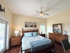 A bedroom with a bed, bedside tables, a dresser, a ceiling fan, and wall art. - Sunset Pointe Retreat  Bay Views • Beach Access • Pool • Kayak, Paddle Board (Port St. Joe)