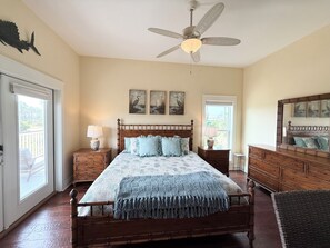 Une chambre à coucher avec un lit en bois, deux tables de chevet, un ventilateur de plafond et des œuvres d’art accrochées au mur.