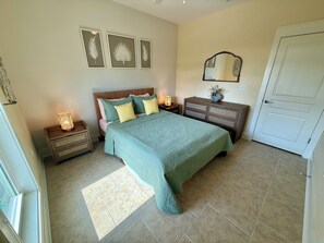 A bedroom with a bed, nightstands, a dresser, a mirror, and wall art. - Sunset Pointe Retreat  Bay Views • Beach Access • Pool • Kayak, Paddle Board (Port St. Joe)