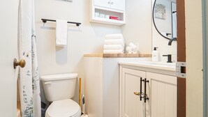 Et badeværelse med toilet, håndvask, spejl og skab.
