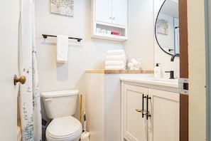 A bathroom with a toilet, a sink, a mirror, and a cabinet.