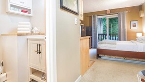 A hotel room with a bed, a desk with a computer, a microwave, and a view of the outdoors. - Fireside Suite, Simple Basecamp at Snowline Lodge (Deming)