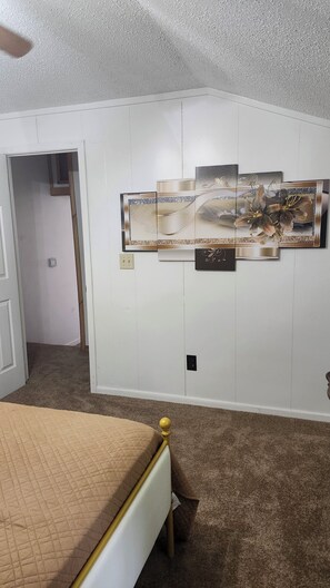 A bedroom with a bed, a wall-mounted artwork, and a door leading to another room. - Creekside Caper (Mount Hope)