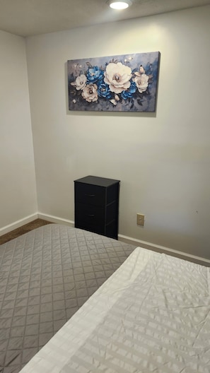 A bedroom with two beds, a small black filing cabinet, and a floral painting on the wall. - Creekside Caper (Mount Hope)