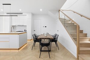 Una cocina moderna con armarios blancos, una mesa de comedor de madera y sillas negras.