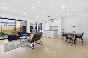 A modern interior with a dining area, kitchen, and living space. - Domi Rentals - The Cheltenham Southland House (Cheltenham)