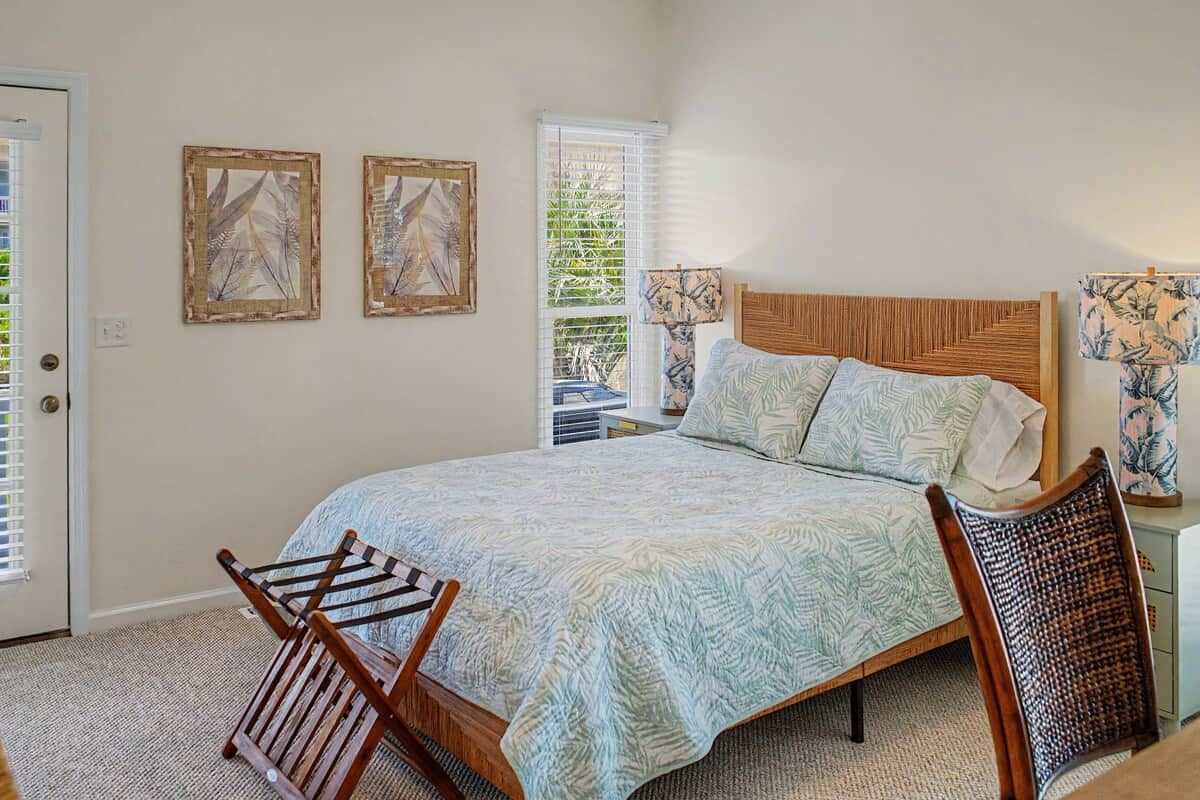 A bedroom with a bed, a chair, a nightstand, and artwork on the walls.