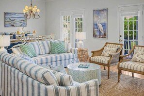 A living room with striped sofas, a round coffee table, and a dining area with a white table and chairs.