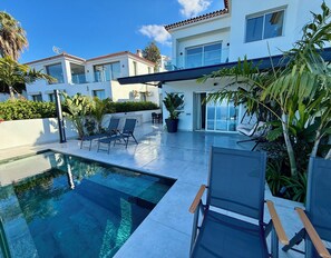 Una casa moderna con piscina, area relax esterna e un'ampia porta scorrevole in vetro.