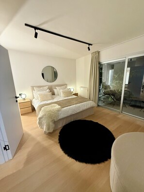 A modern bedroom with a bed, bedside tables, a round mirror, and a view through a glass door. - White House • Relaxation, Views, and an Infinity Pool • (Santa Úrsula)