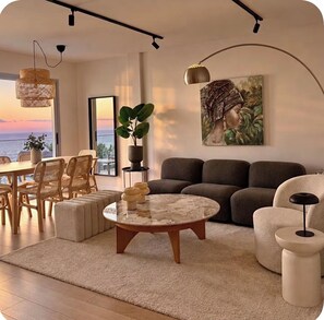 A modern living room with a sofa, a coffee table, and a dining area with chairs. - White House • Relaxation, Views, and an Infinity Pool • (Santa Úrsula)