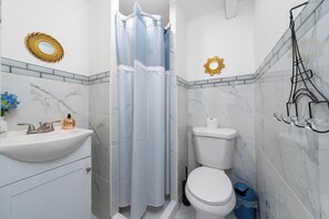 Ein Badezimmer mit einem weißen Waschbecken, einer Toilette, einer Duschvorhang und einem Handtuchhalter.