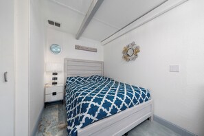 Ein Schlafzimmer mit einem Bett, einem Nachttisch, einer Lampe, einem Spiegel und einem Wandzeichen.