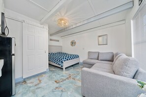 Ein Zimmer mit einem Bett, einem grauen Sofa, einem weißen Kleiderschrank und einem Marmorboden.