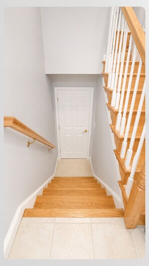 A staircase with wooden steps and white railings, leading to a white door. - Soothing 1-bedroom house with Free Parking in Fort Washington (Fort Washington)
