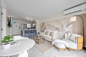 Ein modernes Wohnzimmer mit einem weißen Sofa, einem Couchtisch und einem Essbereich mit weißem Tisch und Stühlen.