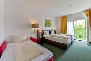 A hotel room with two beds, a red chair, a nightstand with a lamp, and a window with curtains. - Nagerl Landhotel (Marzling)