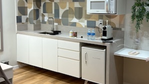 Una kitchenette compacta con microondas, pileta y alacenas.