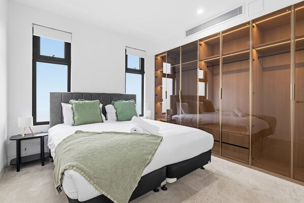 A bedroom with a large bed, a walk-in closet, and a window.