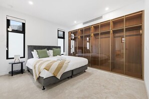 Un dormitorio con cama, mesitas de noche, armario y ventana.