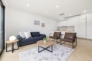 A modern living room with a sofa, chairs, a coffee table, and a rug. - Domi Rentals - The Cheltenham Southland House (Cheltenham)