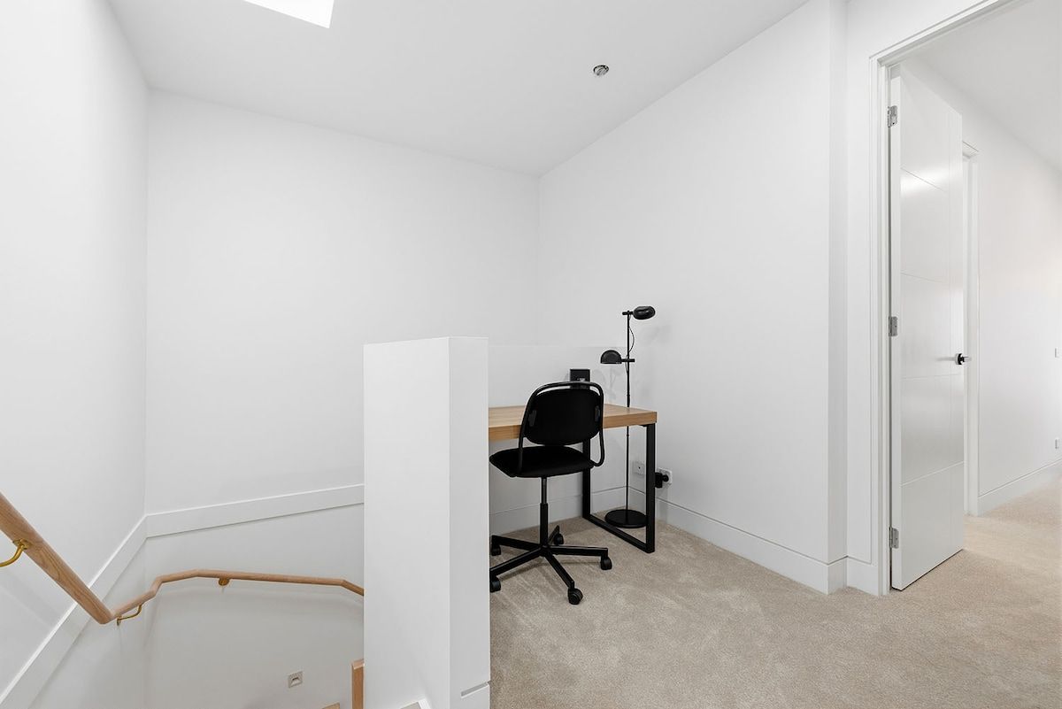 A small, white-walled room with a desk, chair, and a closed door.