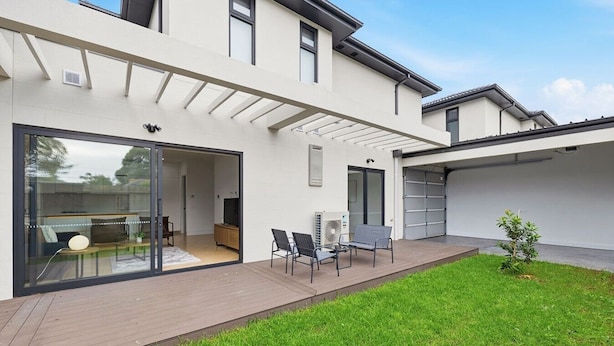 A modern house with a covered patio, a glass door entrance, and a small lawn. - Domi Rentals - The Cheltenham Southland House (Cheltenham)