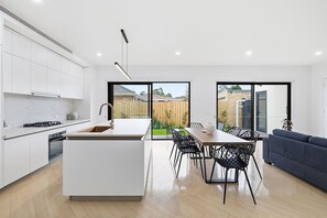 Une cuisine moderne avec un îlot central, un coin repas avec des chaises et un canapé.