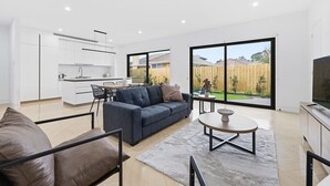 Een modern appartement met een woonkamer, keuken en grote schuifdeuren naar een achtertuin.