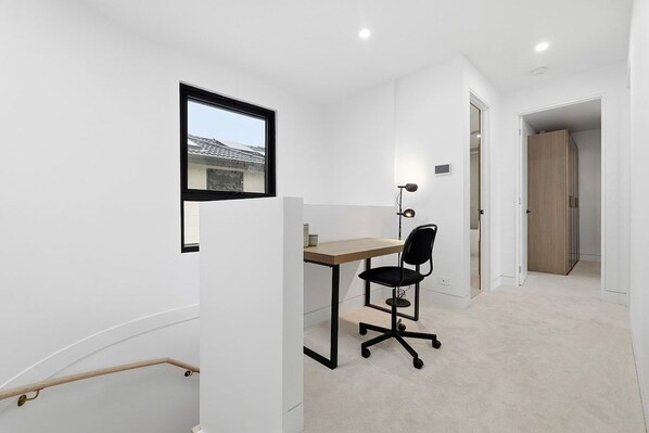 A small, modern office space with a desk, chair, and a view of a building outside.