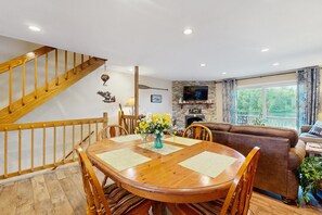 Een eetgedeelte met een houten tafel en stoelen, een bloevas, een open haard en een televisie.