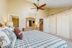 A bedroom with a bed, a ceiling fan, a dresser, a mirror, and a staircase. - Lakeside Escape:  views and walk to beach (Center Ossipee)