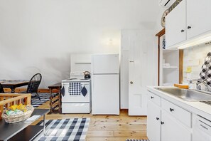 Eine kleine Küche mit Herd, Kühlschrank und Spüle.