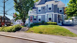 A two-story house with a front porch, a red door, and a white picket fence. - 1 BR plus downtown - walk to Beaches/ Eateries (Kennebunkport)