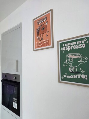 Eine Küche mit Kühlschrank, Backofen und zwei gerahmten Bildern an der Wand.