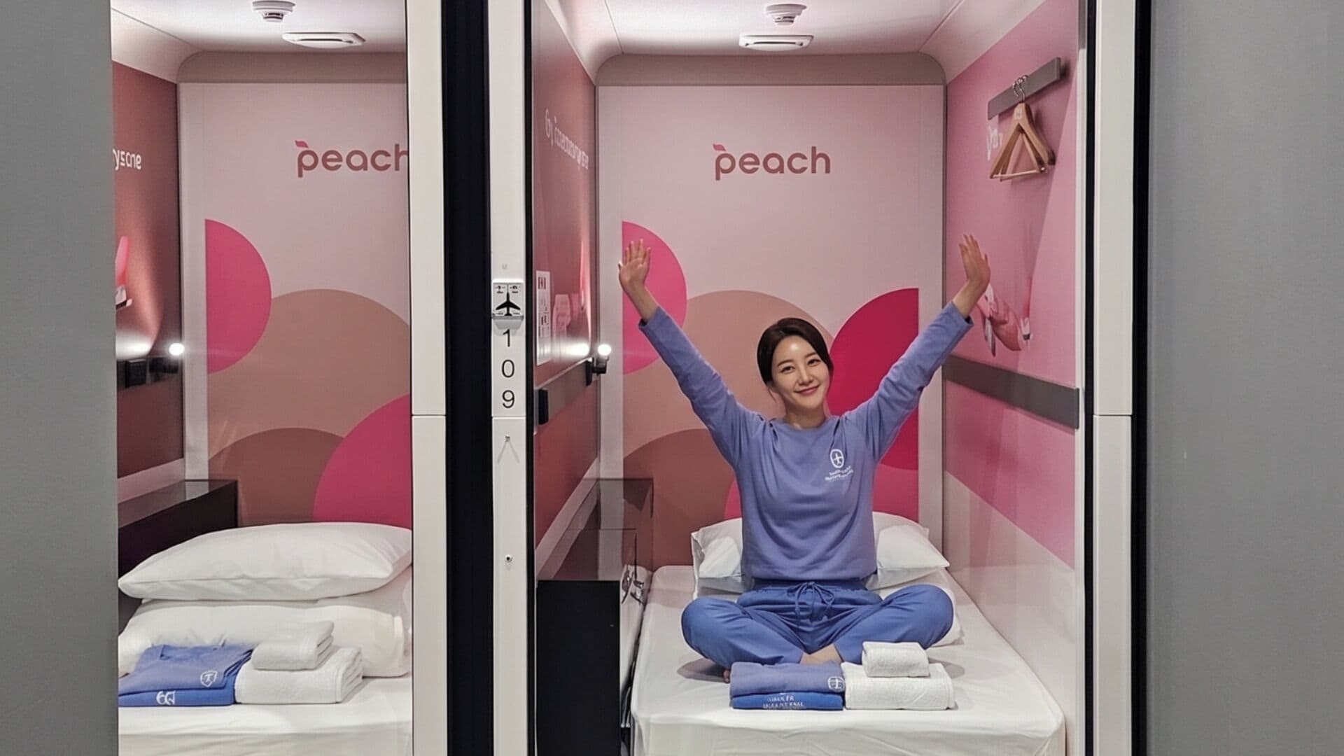 A room with a bed, a wall-mounted towel dispenser, and a wall with the word 'peach' visible.