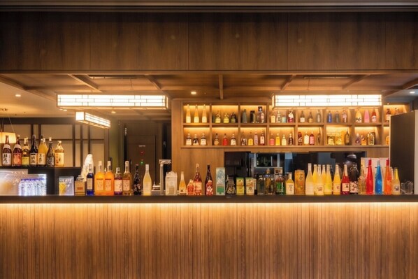 A bar area with wooden paneling and shelves stocked with various bottles.
