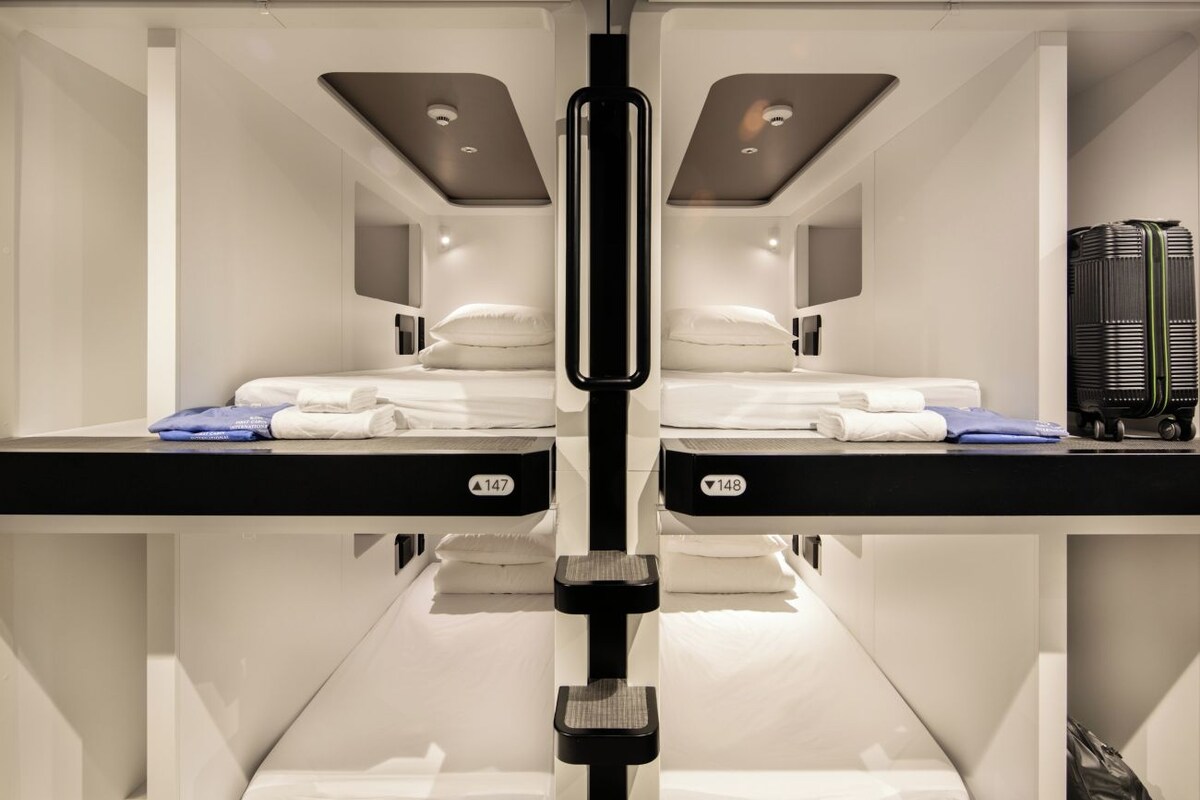 A mirrored room with two beds, a central column, and a black heater on the right.