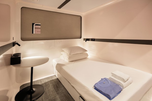 A compact hotel room with a bed, a small table, and a wall-mounted shelf. - FIRST CABIN SEOUL MYEONGDONG (Seoul)