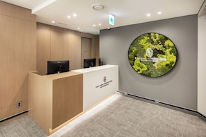 A reception area with a wooden reception desk, a circular wall decoration, and a grey carpeted floor.
