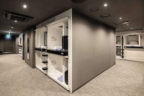 A hotel room with a minibar, a bed, and a bathroom with a shower and toilet.