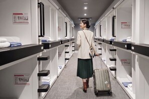 A hotel corridor with rows of rooms, each with a bed, a nightstand, and a wall-mounted phone. - FIRST CABIN SEOUL MYEONGDONG (Seoul)
