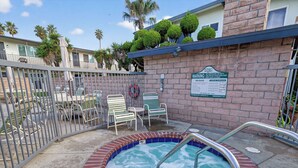 Un espace spa comprenant un jacuzzi, des chaises longues et un mur de briques sur lequel est apposée une enseigne.