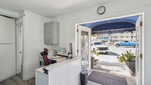 Un espace d’accueil avec un bureau, un ordinateur et une horloge au mur.