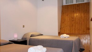 A hotel room with two beds, each with a grey bedspread and pillows, and a wooden wall paneling. - Apartamentos Good Stay Atocha (Madrid)