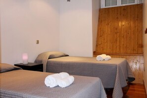 A hotel room with two beds, each with a grey bedspread and pillows, and a wooden wall paneling. - Apartamentos Good Stay Atocha (Madrid)