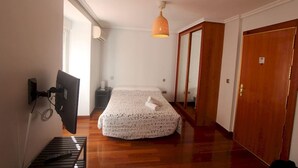 A bedroom with a bed, a desk, a chair, a hanging lamp, and a wardrobe. - Apartamentos Good Stay Atocha (Madrid)